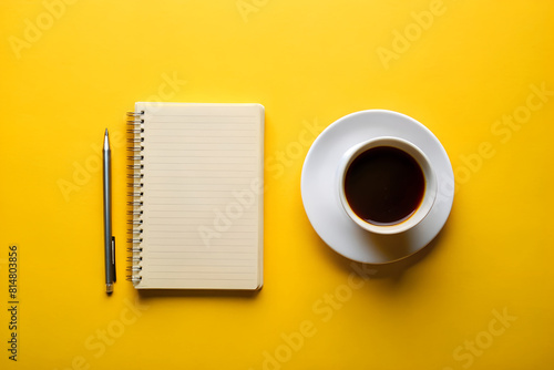 There is a cup of coffee,pen and a notebook on a yellow background. Notepad, Office supply, Stationery.