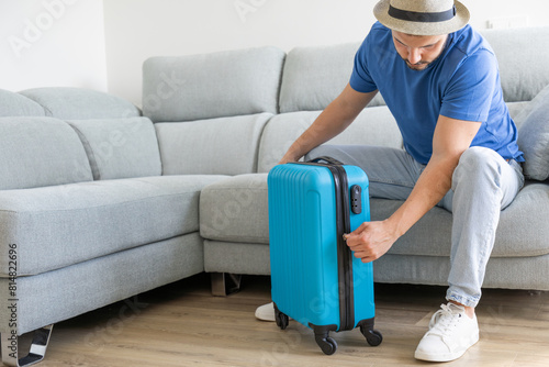 man closing his carry-on suitcase at home © Lucia PSV