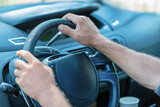 Man gripping the steering wheel while driving a car on a sunny day