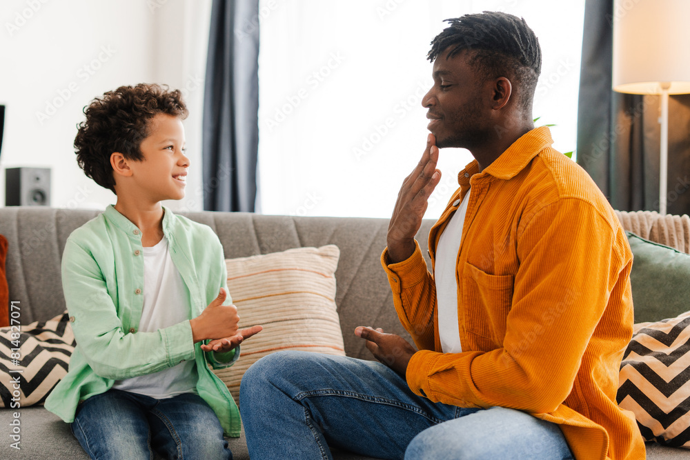 Happy, positive African American little boy and his dad communicating with sign language Happy, positive African American little boy and his dad communicating with sign language