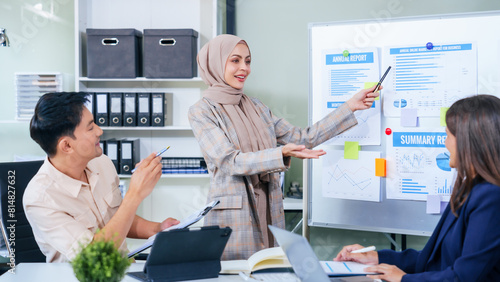 Foto A multicultural team of professionals, including male and female businesspersons, convenes around a desk with tablets, discussing strategies illustrated on a whiteboard during a dynamic presentation