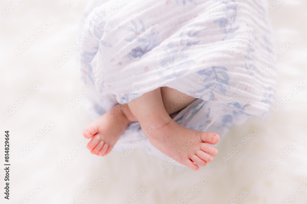 Newborn baby is wrapped in a blue blanket with his legs crossed. Newborn baby is wrapped in a blue blanket with his legs crossed.