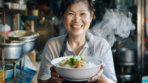 Chinese woman smiling as she holds a steaming bowl of traditional congee