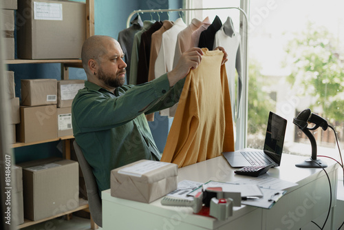 Fényképezés Online shopping business concept, male entrepreneur checks order on laptop and checks whether it is the dress
