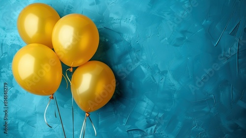   Yellow Balloons on a Blue Wall - A string attaches one balloon to the blue wall photo
