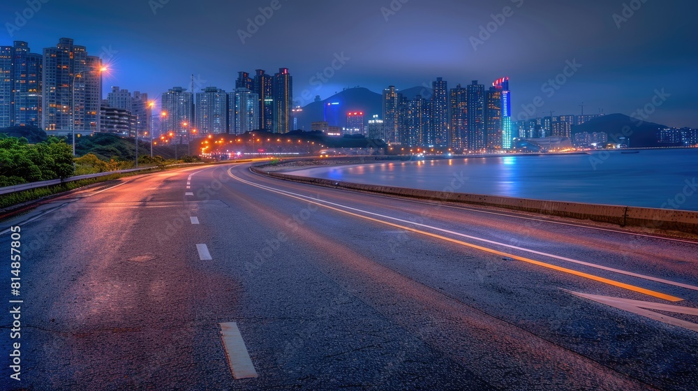 a city skyline adorned with modern buildings at sunset, with a clear asphalt road and the shimmering sea water surface in the foreground, illuminated to mimic the lights of urban skyscrapers at night.