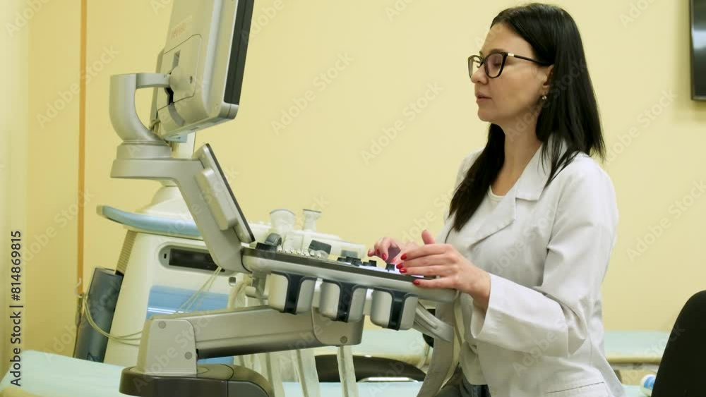 A woman doctor works at an ultrasound machine in a clinic. A woman doctor works at an ultrasound machine in a clinic.