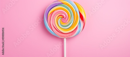 On a pink pastel background there is a delightful flat lay image showcasing a minimalist Sweet Treat Swirl Candy Lollipop marshmallow with a vibrant and colorful pattern while leaving empty space for