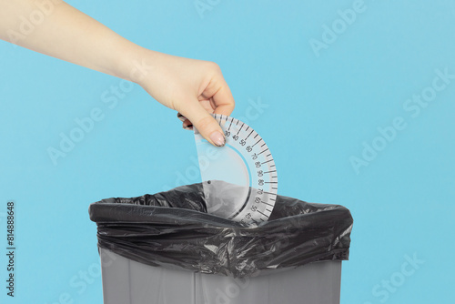throw protractor in the trash, outstretched arm with protractor in front of trash can, plastic recycling concept