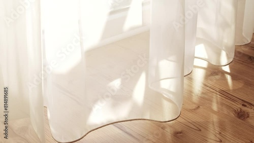 Transparent white curtain tulle moves from the wind from an open window. Sunny day, the sun's rays sunlight penetrate the room.	