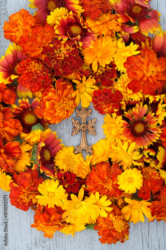 orange-red colorful flowers and wooden christian cross on table. top view. Symbol of the death and resurrection of Jesus Christ  Faith of God  Hope  Love. Religious church holiday
