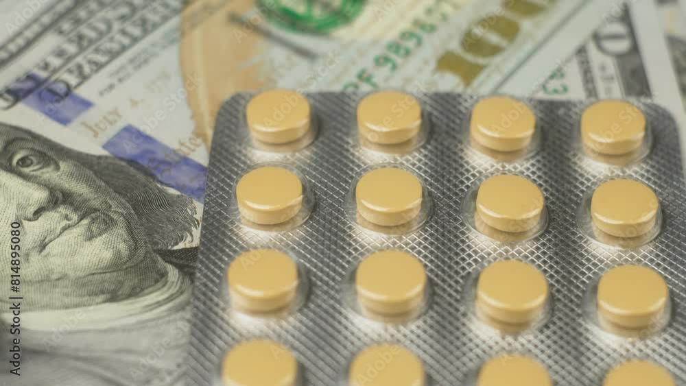 Medicine in pills on top of 100 Dollar Banknotes. Blister of drugs, yellow tablet. Investments in hospitals, high cost of treatment. macro shot in slow motion. Pills in blister on dollar bills Medicine in pills on top of 100 Dollar Banknotes. Blister of drugs, yellow tablet. Investments in hospitals, high cost of treatment. macro shot in slow motion. Pills in blister on dollar bills