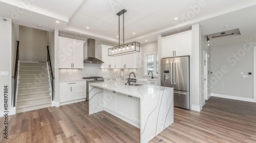 Beautiful white kitchen in new luxury home  with waterfall island  stainless steel appliances  and hardwood floors