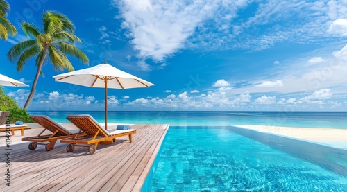 Photo of an infinity pool with a wooden deck  beach chairs and umbrella overlooking the ocean.