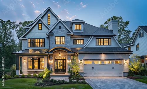 Exterior front view of an elegant luxury home with car garage. Traditional architecture style and modern details, shingle or wood roof. There is green grass in yard, illuminated by warm lights.