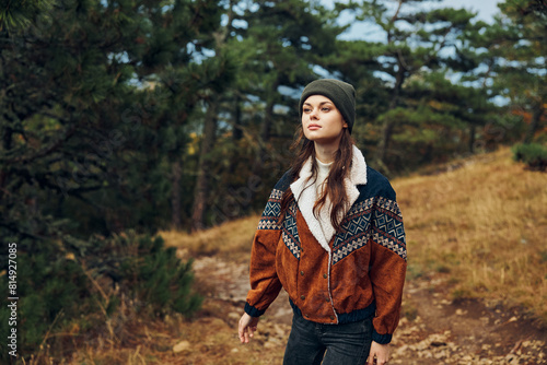 A stylish young woman in a fashionable hat and jacket confidently exploring a tranquil forest path surrounded by nature © SHOTPRIME STUDIO