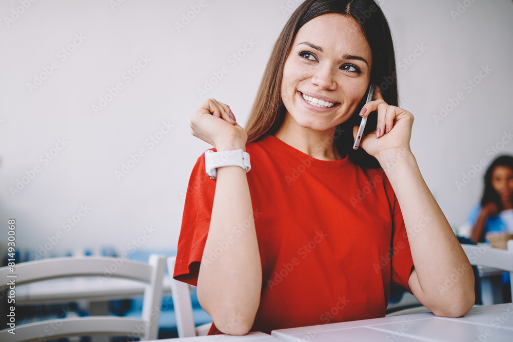 Positive cheerful woman looking away while discussing time of meeting with friend via application on cellular phone, smiling woman feeling excited of received good news via telephone conversation Positive cheerful woman looking away while discussing time of meeting with friend via application on cellular phone, smiling woman feeling excited of received good news via telephone conversation