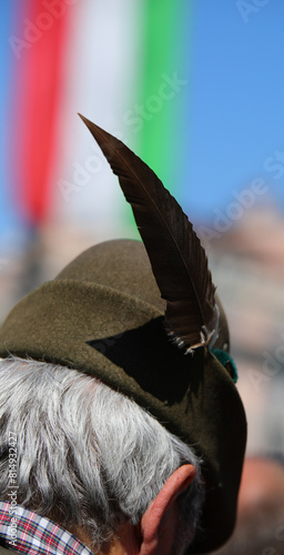 Italian man wearing an Alpini hat with a black feather and the Italian flag