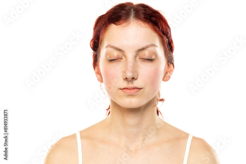 Portrait of a young serious woman without makeup, closed eyes and nose piercing on a white background