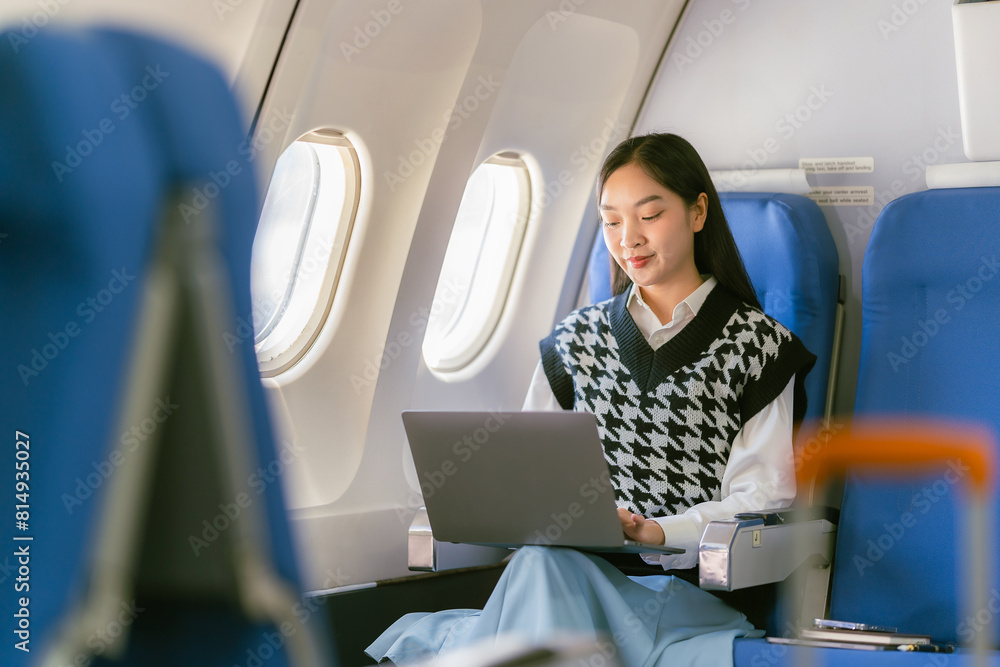 Professional Asian woman using laptop on airplane While sitting near the window in first class on an airplane during a flight travel concept Professional Asian woman using laptop on airplane While sitting near the window in first class on an airplane during a flight travel concept
