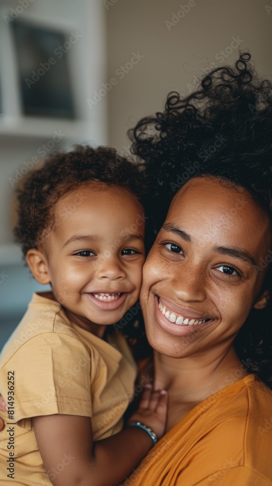 A joyful mother and child moment with the mother's curly hair and warm smile and the child's innocent and happy expression set against a blurred indoor background. A joyful mother and child moment with the mother's curly hair and warm smile and the child's innocent and happy expression set against a blurred indoor background.