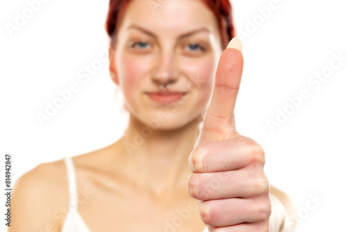 portrait of a young woman with red hair showing thumb up on white background