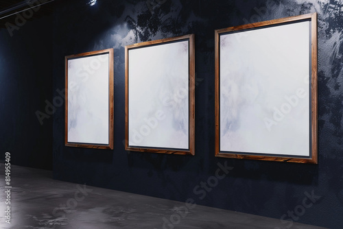 From an side  a gallery wall showcases a trio of wooden frames  each enclosing a white canvas  against a wall painted in a deep  matte black exhibit exhibit