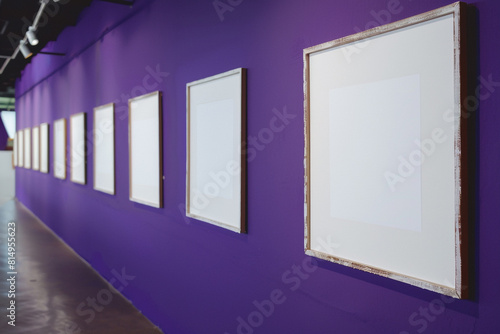 In the gallery, a series of frames are mounted against a wall of deep, Majestic Purple. Each frame, enclosing a white space, 