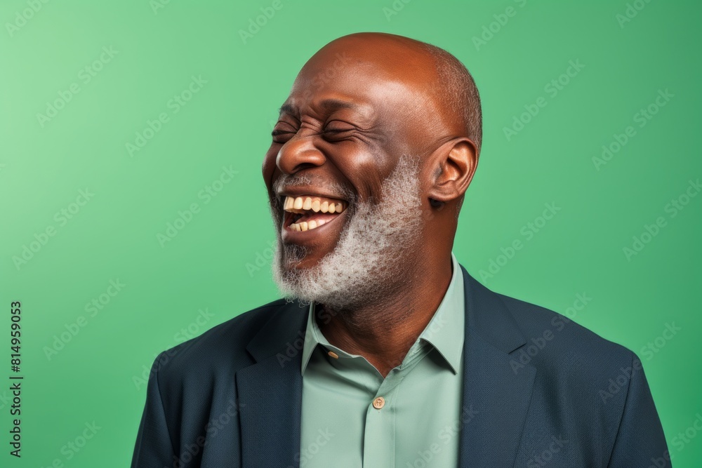 Portrait of a glad afro-american man in his 50s laughing on pastel green background Portrait of a glad afro-american man in his 50s laughing on pastel green background
