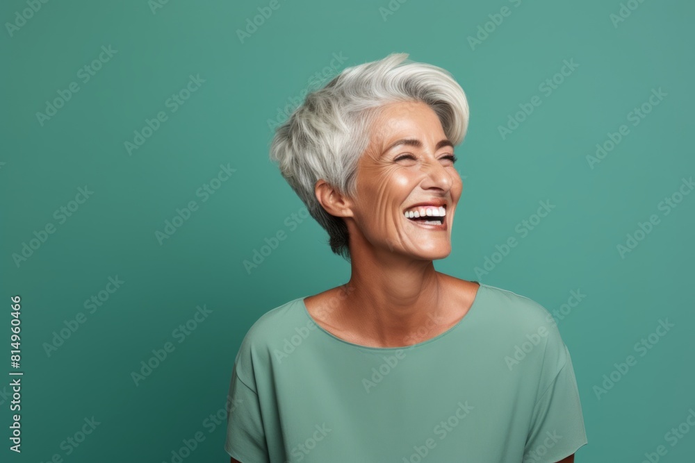 Portrait of a glad woman in her 60s laughing isolated on pastel green background Portrait of a glad woman in her 60s laughing isolated on pastel green background