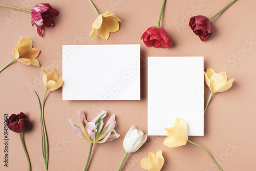 Fototapeta Naklejka Na Ścianę i Meble -  Beautiful aesthetic flowers with empty paper blank on neutral background top view. Minimal invitation or greeting card.