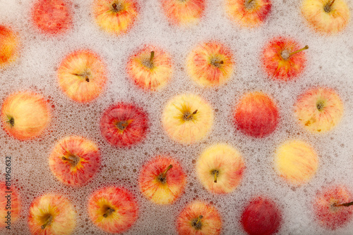 Washing fruits. Autumn crop apples washed in water with antibacterial foam. Ripe apples swimming on water surface, top view