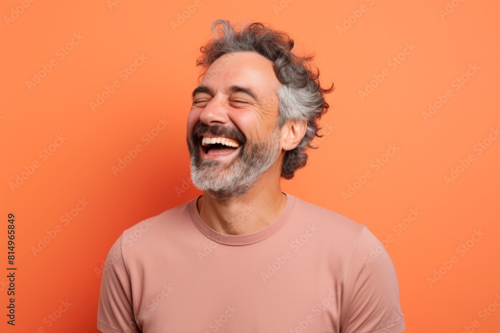 Portrait of a satisfied man in his 40s laughing in front of pastel orange background Portrait of a satisfied man in his 40s laughing in front of pastel orange background