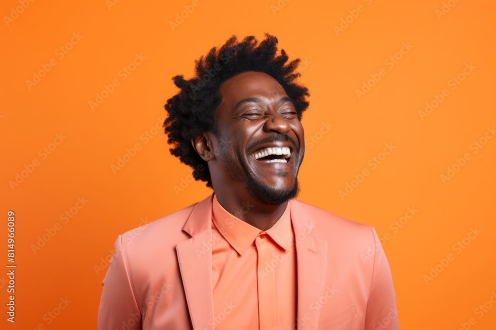 Portrait of a jovial afro-american man in his 40s laughing isolated on pastel orange background Portrait of a jovial afro-american man in his 40s laughing isolated on pastel orange background