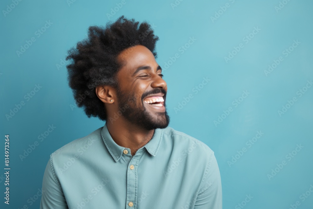 Portrait of a blissful afro-american man in his 40s laughing in front of pastel teal background Portrait of a blissful afro-american man in his 40s laughing in front of pastel teal background