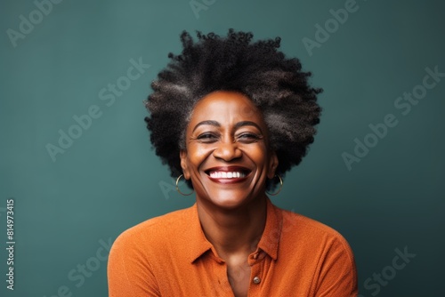 Portrait of a content afro-american woman in her 50s smiling at the camera in pastel teal background