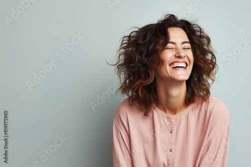 Portrait of a joyful woman in her 30s laughing isolated in pastel gray background