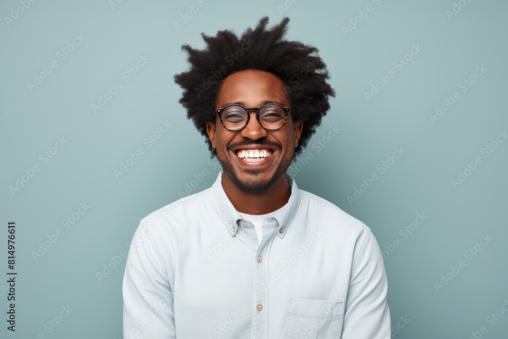 Obraz premium Portrait of a merry afro-american man in his 30s smiling at the camera while standing against pastel gray background