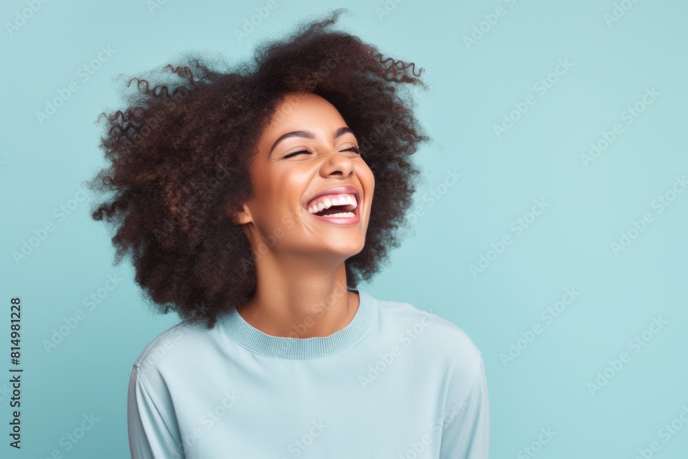 Portrait of a joyful afro-american woman in her 20s laughing while standing against pastel gray background Portrait of a joyful afro-american woman in her 20s laughing while standing against pastel gray background