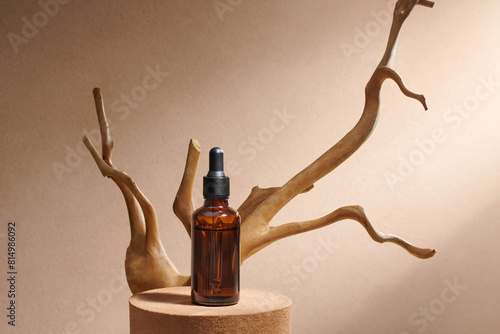 A glass bottle with a cosmetic product and a natural dry branch photo