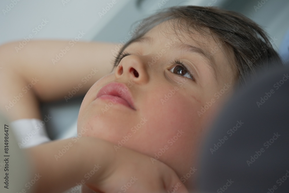 A young child looks up thoughtfully while lying down, capturing a moment of quiet contemplation. A young child looks up thoughtfully while lying down, capturing a moment of quiet contemplation.