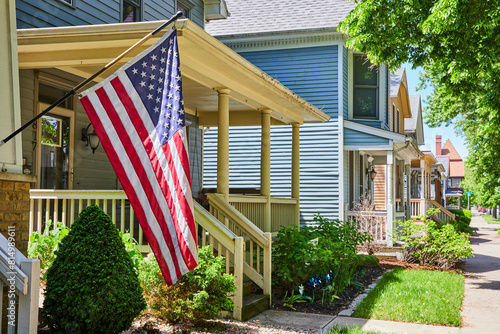 Sunny Suburban Street with American Flag and Lush Gardens, Eye-Level View photo