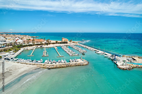 Aerial shot, drone point of view panoramic image of Torre de la Horadada townscape with sandy beach, turquoise bay waters and harbor with vessels at sunny summer day. Costa Blanca, Alicante, Spain © Alex Tihonov