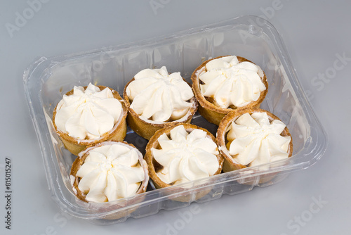 Small fruit tarts with custard top in plastic food packaging photo