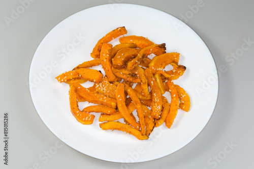Baked slices of butternut squash on dish on gray background © An-T