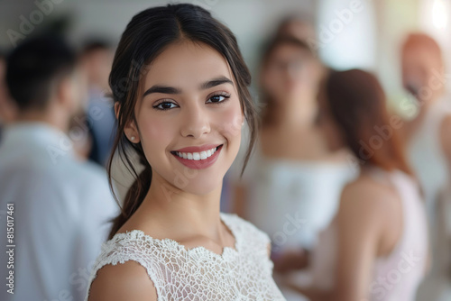 Charming young woman with a captivating smile poses at a social gathering, surrounded by blurred figures in conversation, showcasing a moment of joy and elegance in a festive atmosphere Free Download Charming young woman with a captivating smile poses at a social gathering, surrounded by blurred figures in conversation, showcasing a moment of joy and elegance in a festive atmosphere - GFXLoad