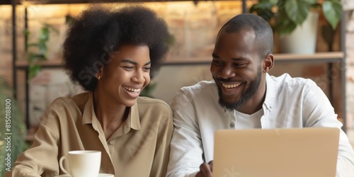 Two cheerful individuals engaged in a fun activity on a laptop, sharing a warm, joyful moment together at a cozy location