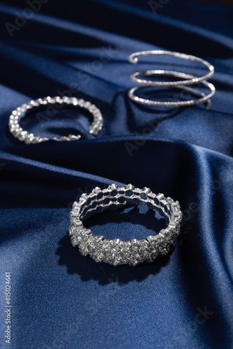 Bracelets with diamonds on a background of blue silk. Expensive jewelry. Natural gems. Top view. Space for text.