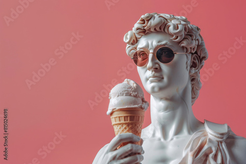 White greek David statue with black sunglasses posing on a pink background, humorously holding a classic vanilla ice cream cone photo