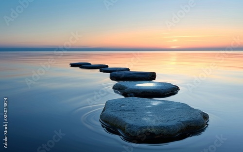 Smooth stones on calm water at sunset  creating a serene path.